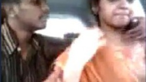 A Tamil man kisses and fondles the breasts of a pretty Asian girl in a car